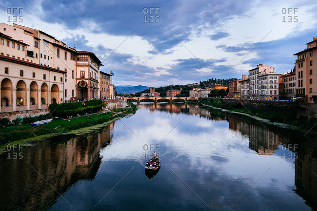 Boat on the Arno River at dusk in Florence, Italy