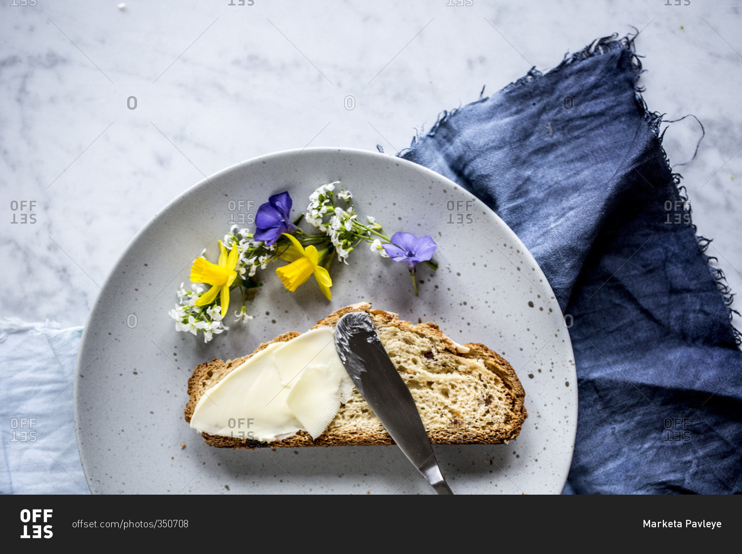 Overhead view of plate of slice of bread with butter and spring flowers