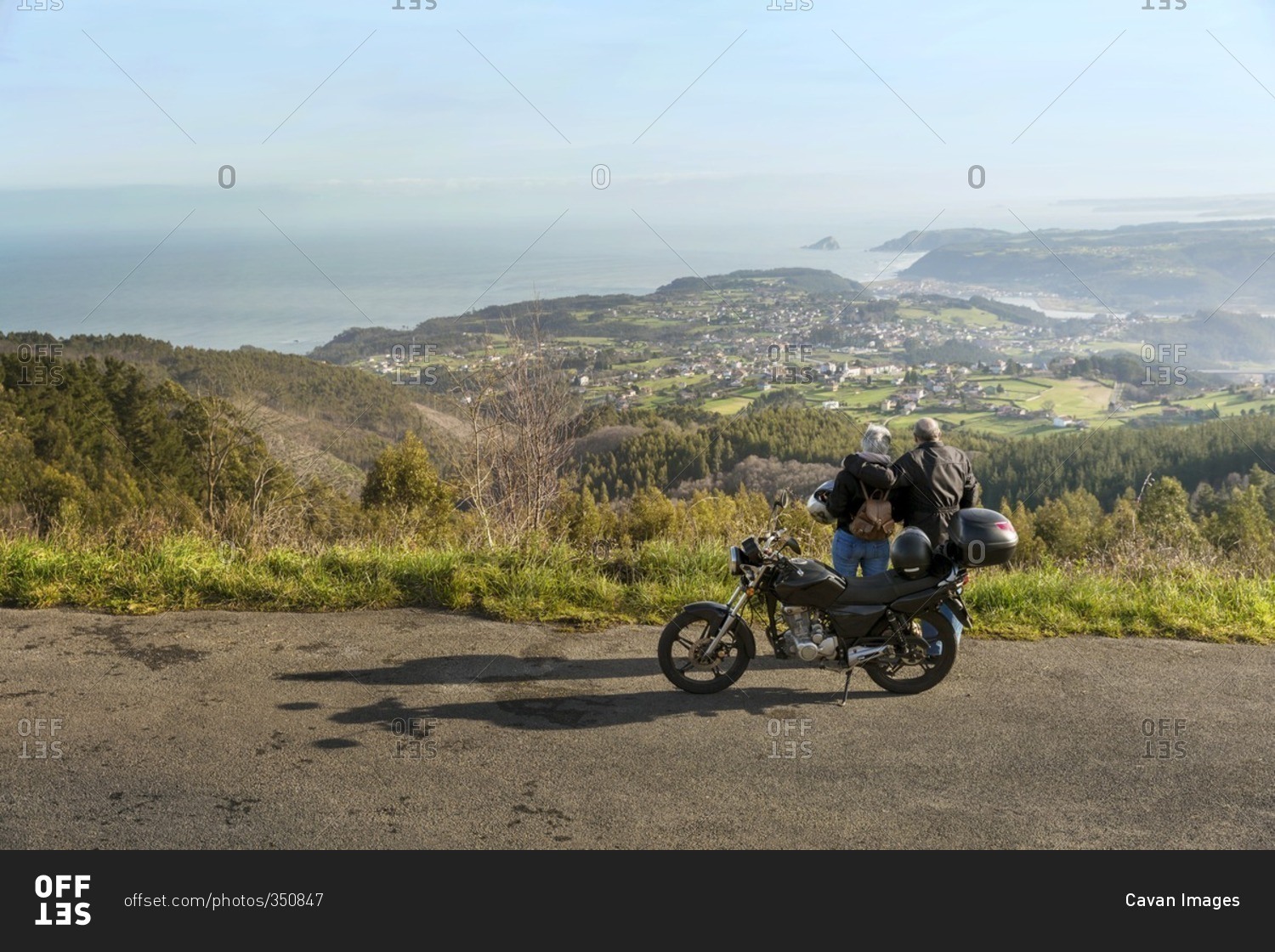 Couple standing by motorcycle enjoying the view from a cliff