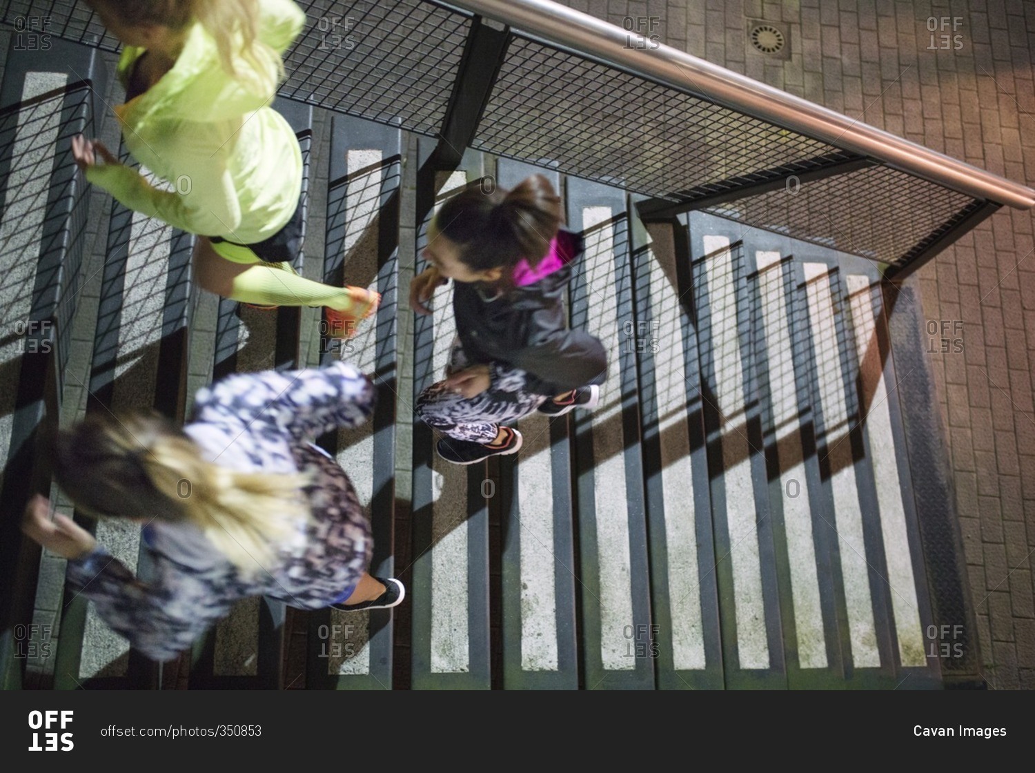 Overhead view of three women running up stairs during night workout