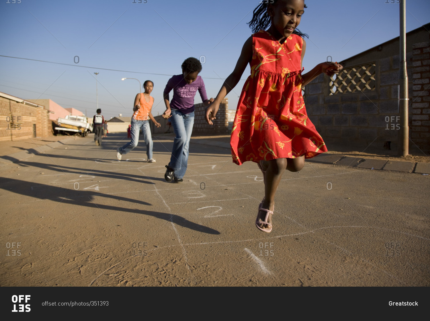 Children playing hopscotch in the street stock photo - OFFSET