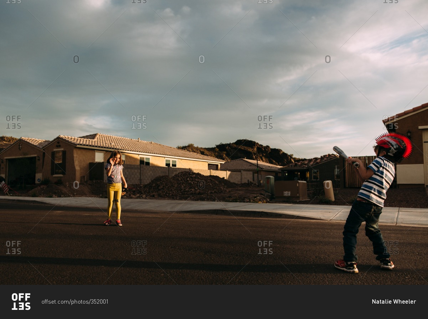 Sister and brother playing baseball in the street