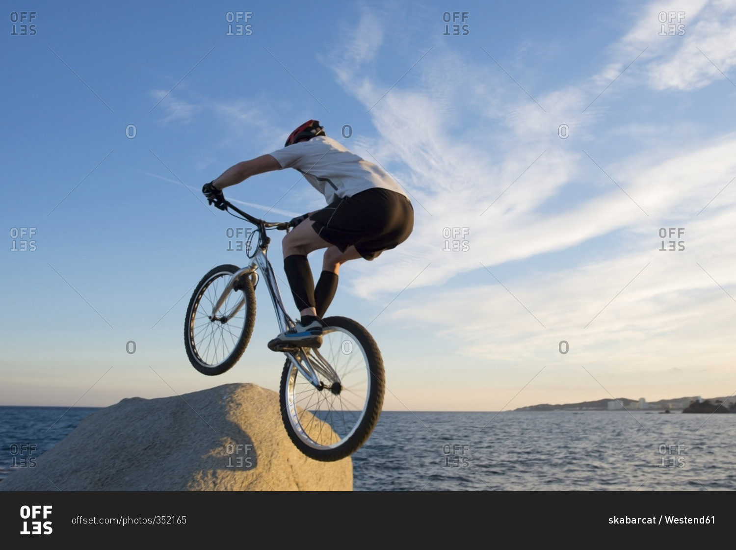 Bmx rider jumping on a rock in the evening