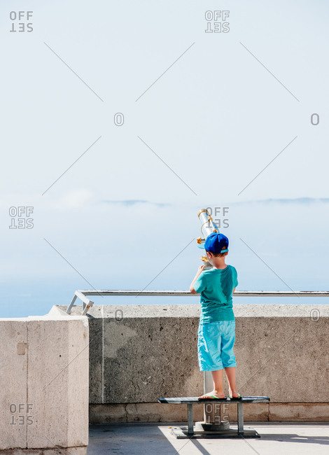 Boy looking through a sightseeing telescope