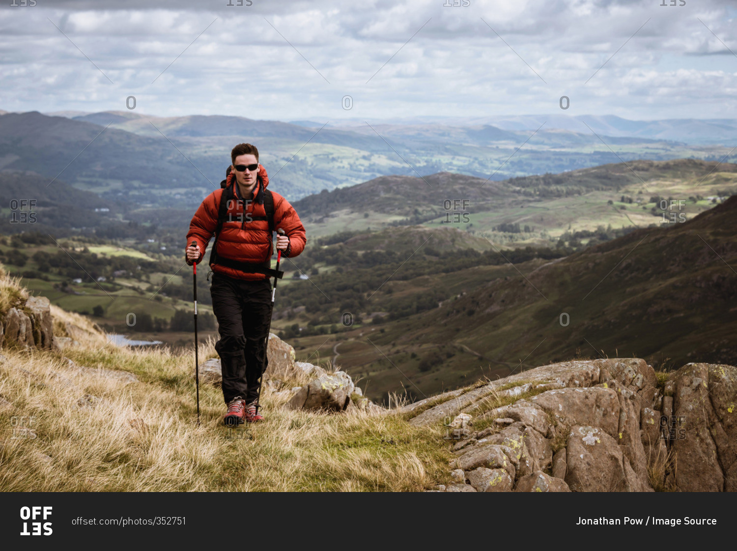 Young male hiker hiking up mountain, The Lake District, Cumbria, UK