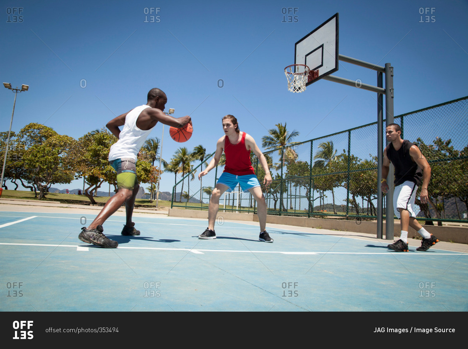 Three men practicing basketball on basketball court