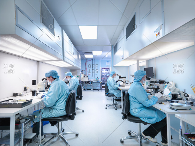 Electronics workers in clean room assembling electronic components