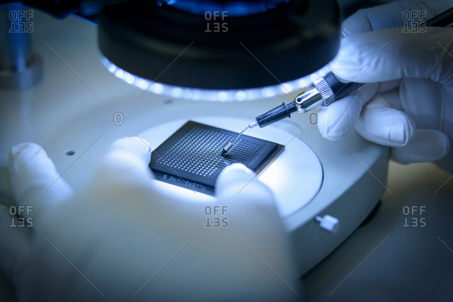 Electronics worker checking small electronic chips in clean room laboratory, close up