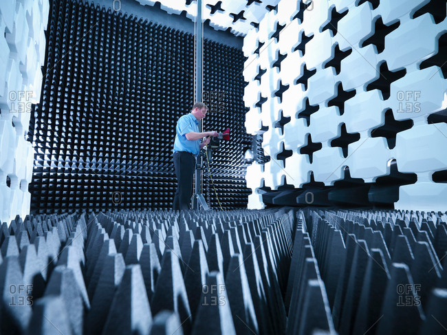 Engineer in anechoic chamber with horn antenna set up for Electromagnetic compatibility (EMC) radiated emission testing