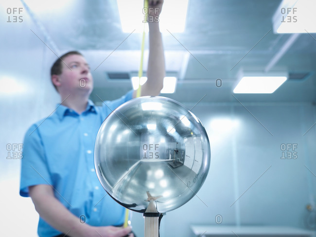 Engineer checking height of equipment under test (EUT) with Van Der Hoofden Head used during electromagnetic field (EMF) safety testing of electronic lighting in foreground