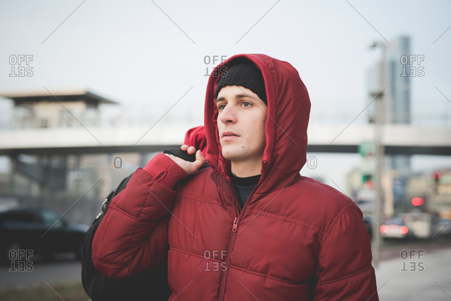Young man wearing red hooded anorak on city street