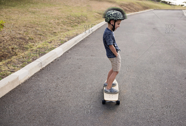 Little boy riding a skateboard with hand in his pockets