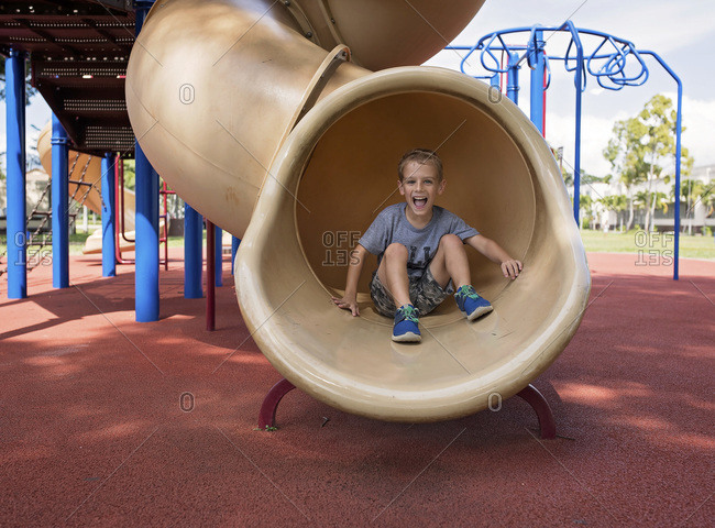 Little boy sliding down a twisty slide