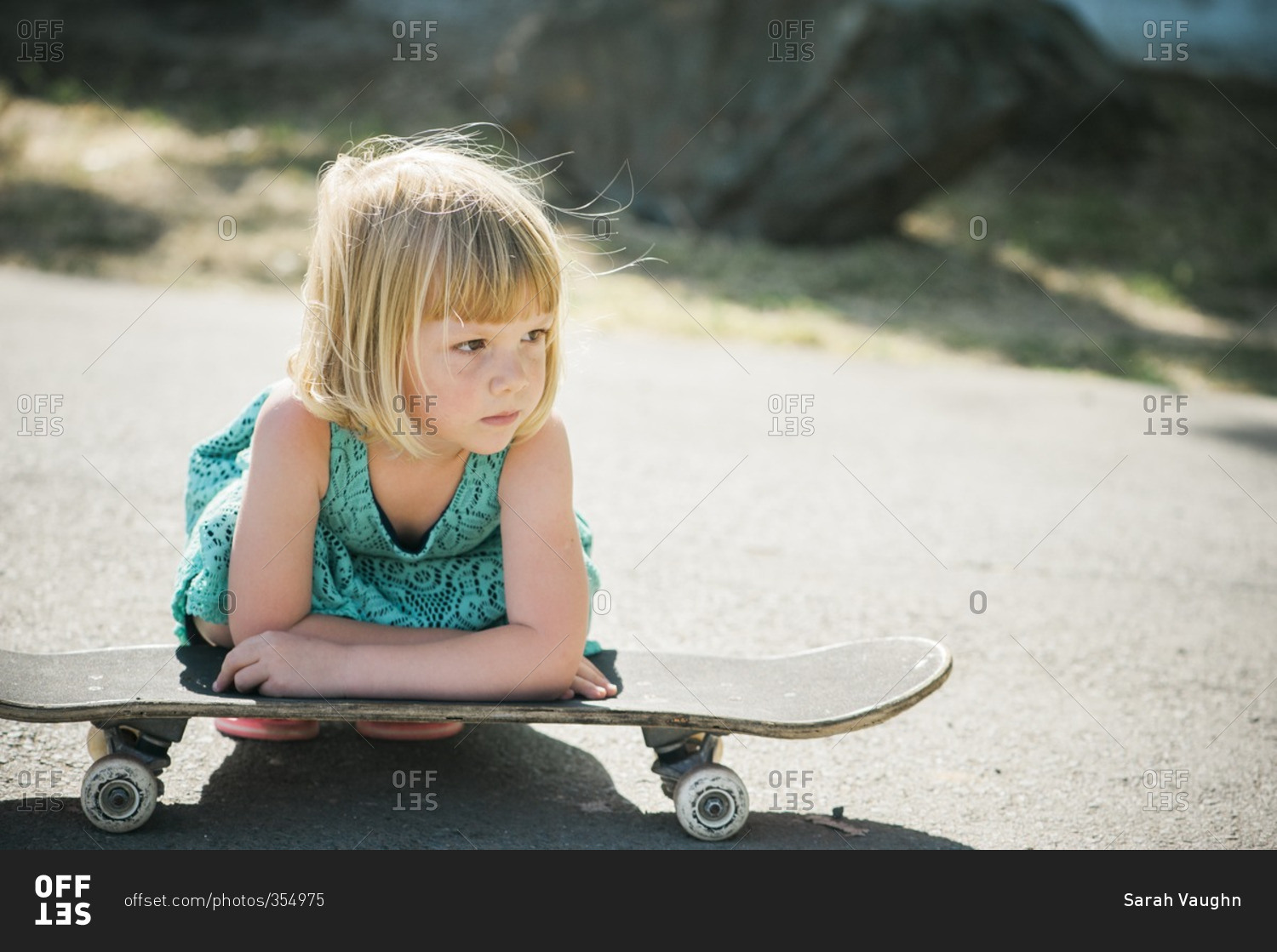 Little girl resting on a skateboard in street