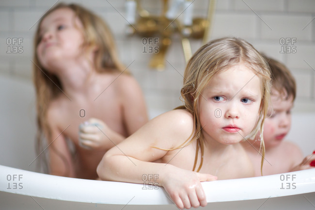 Little Girl In Bathtub With Siblings Looking With Curiosity