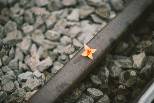 Orange paper origami flower on a train track rail