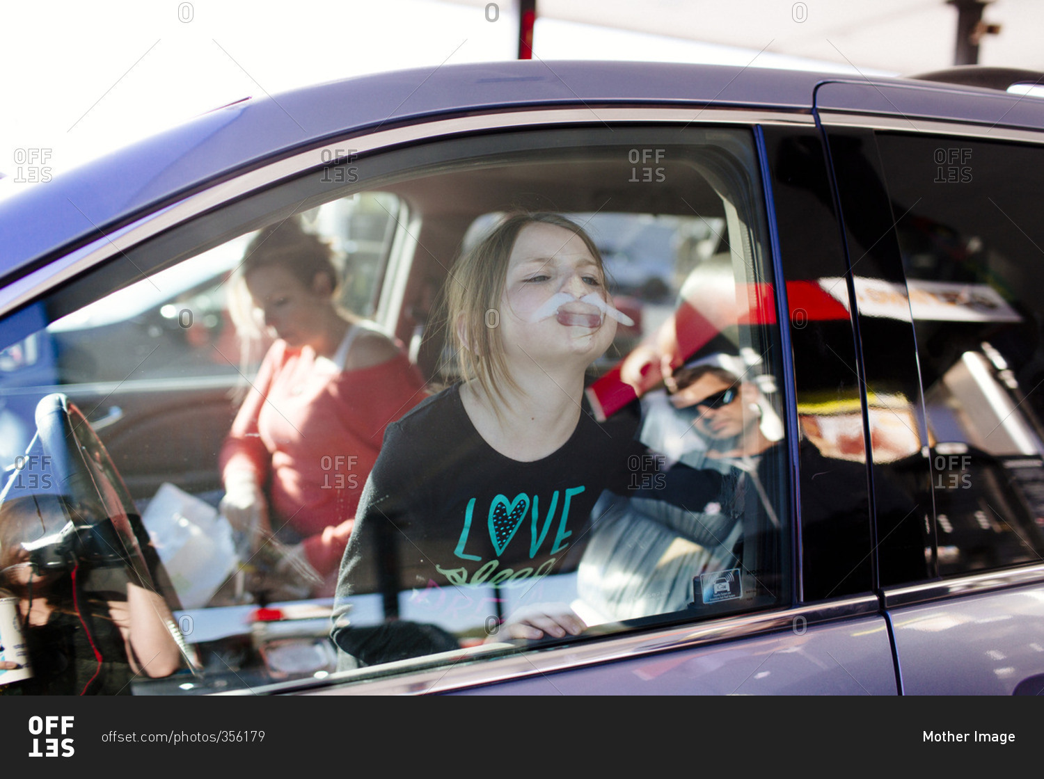 Girl pressing her face against the window of her car and making silly