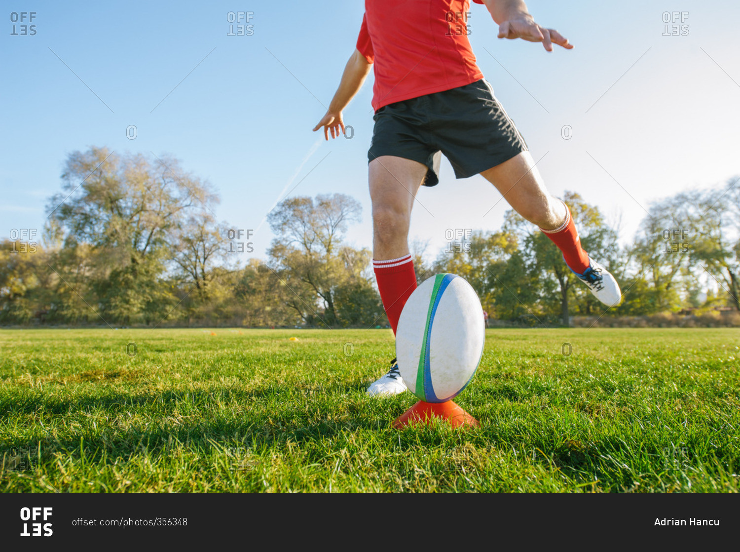Powerful man kicking the ball for a goal on rugby field stock photo