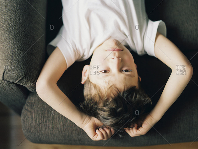 Boy lying upside down on chair