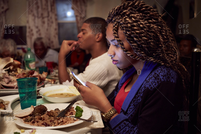 Teenage girl using cell phone at dinner table