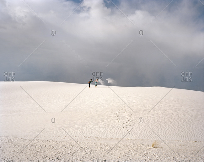 Two women playing with sand in the desert in White Sands, New Mexico