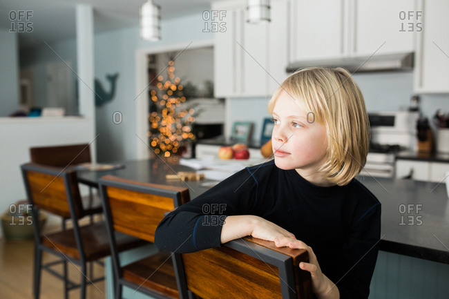 Portrait of a young girl sitting on a chair in the kitchen stock