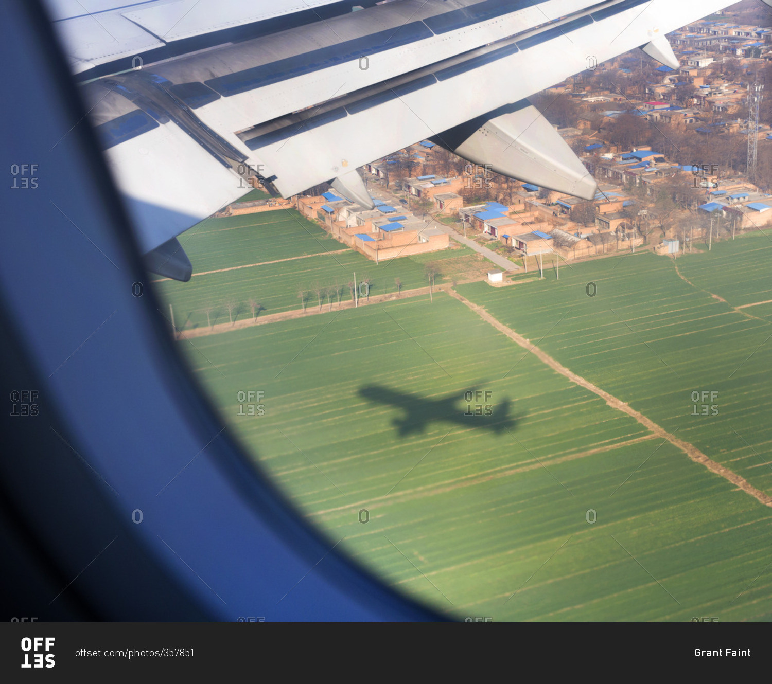 An airplane casting a shadow on a field as it approaches Shanghai Pudong International Airport in Shanghai, China