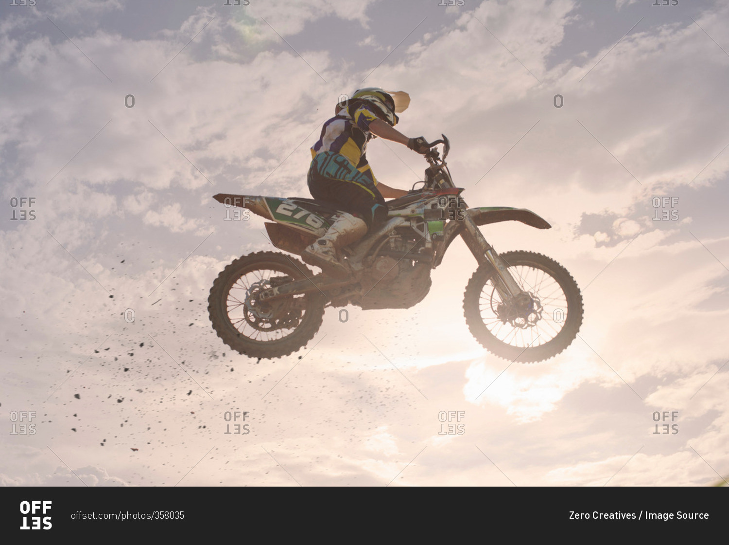 Silhouetted young male motocross racer jumping mid air