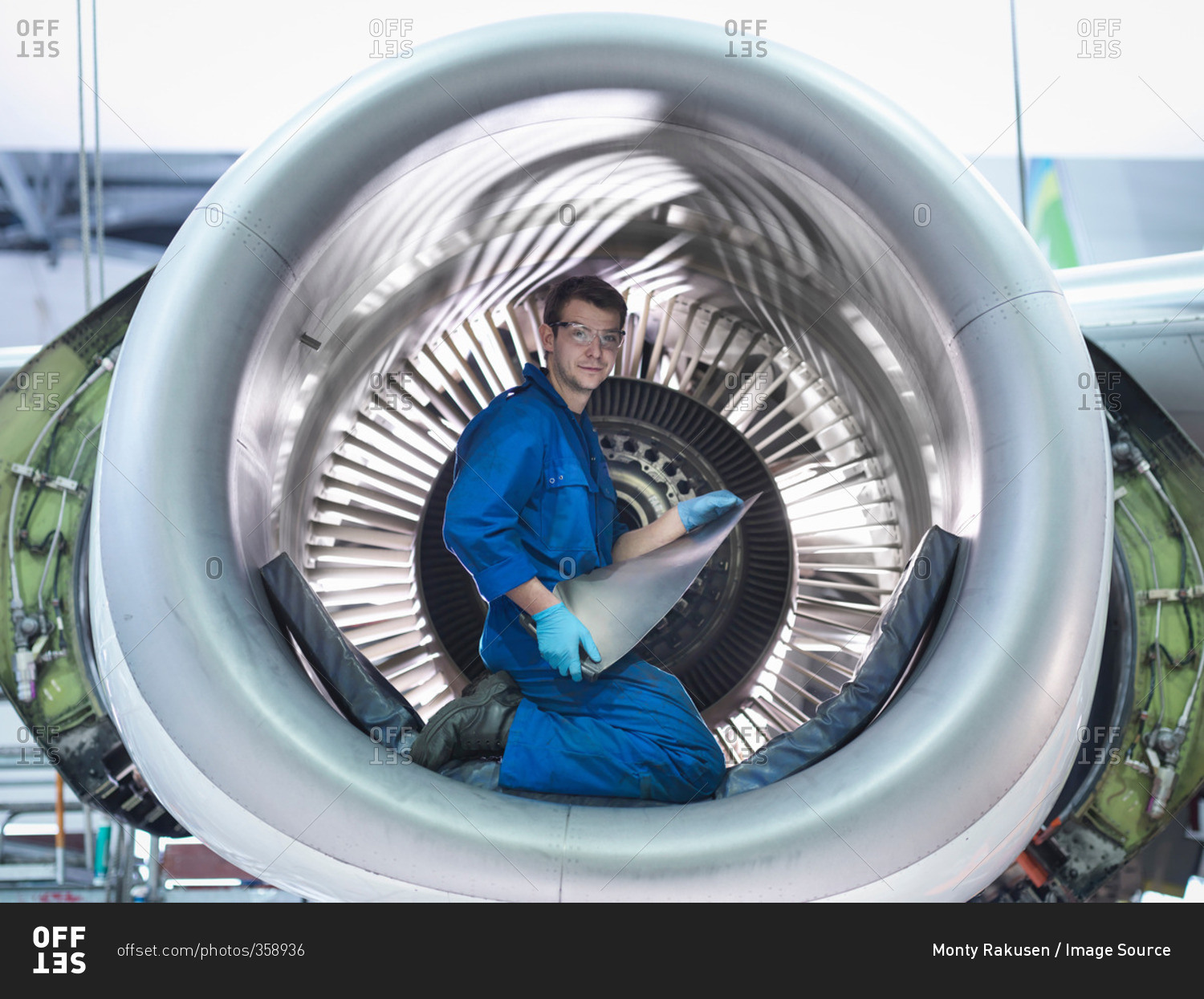 Portrait of an engineer holding jet engine turbine blade in aircraft maintenance factory