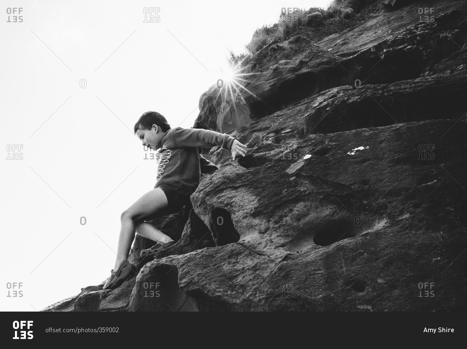 Boy climbing down the side of a steep rocky hill