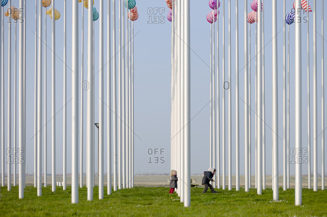 Two young siblings running through an art installation by Daniel Buren