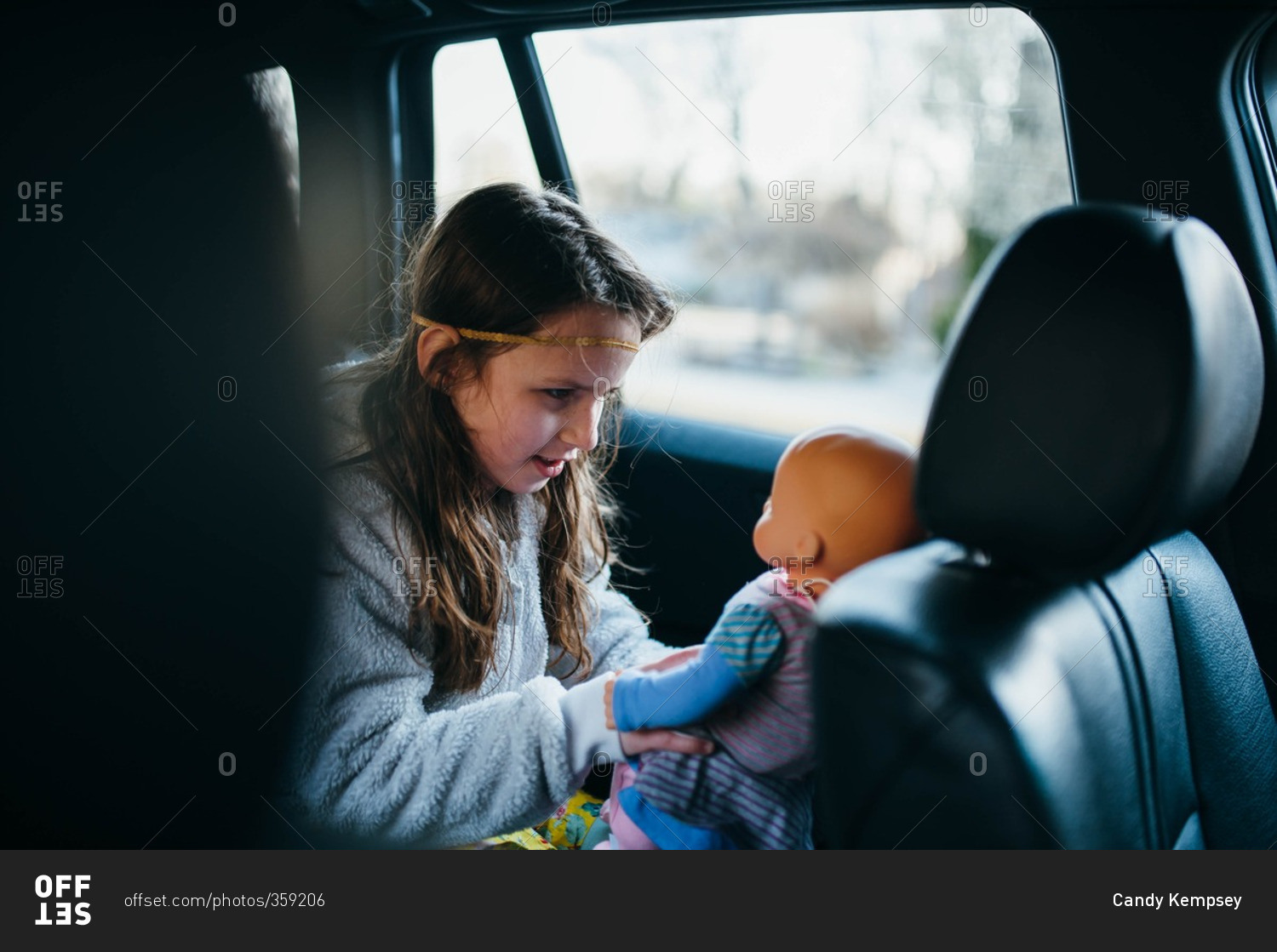 Girl in back seat of car playing with her doll