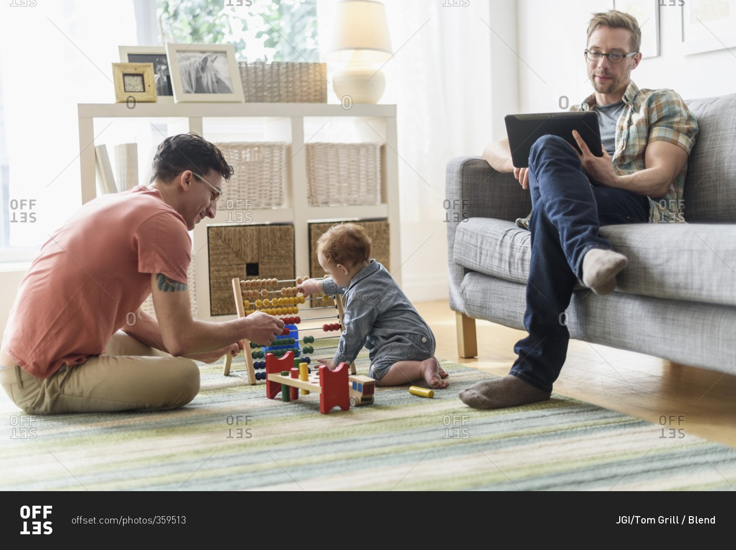 Caucasian gay fathers and baby relaxing in living room