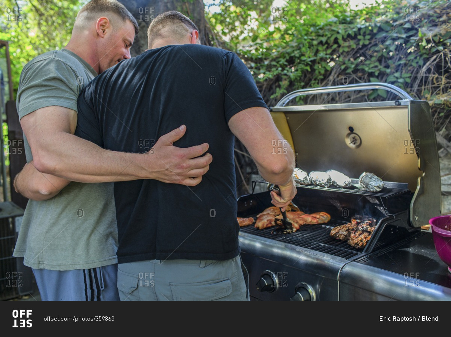 Gay couple grilling food in backyard
