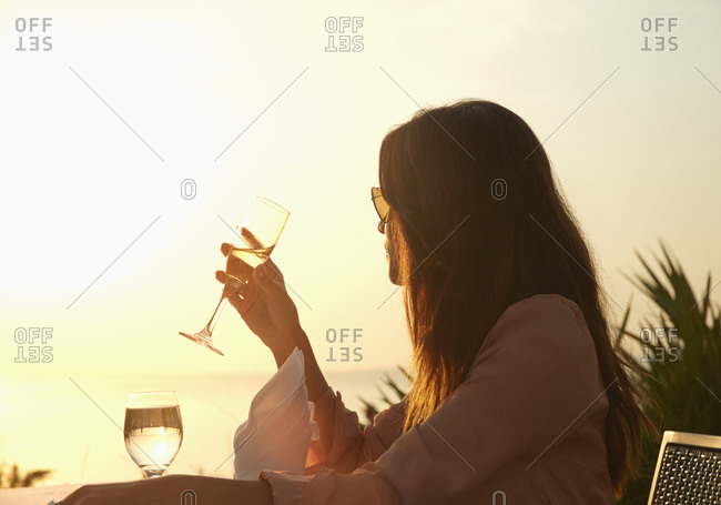Hispanic woman drinking champagne at sunset dinner outdoors