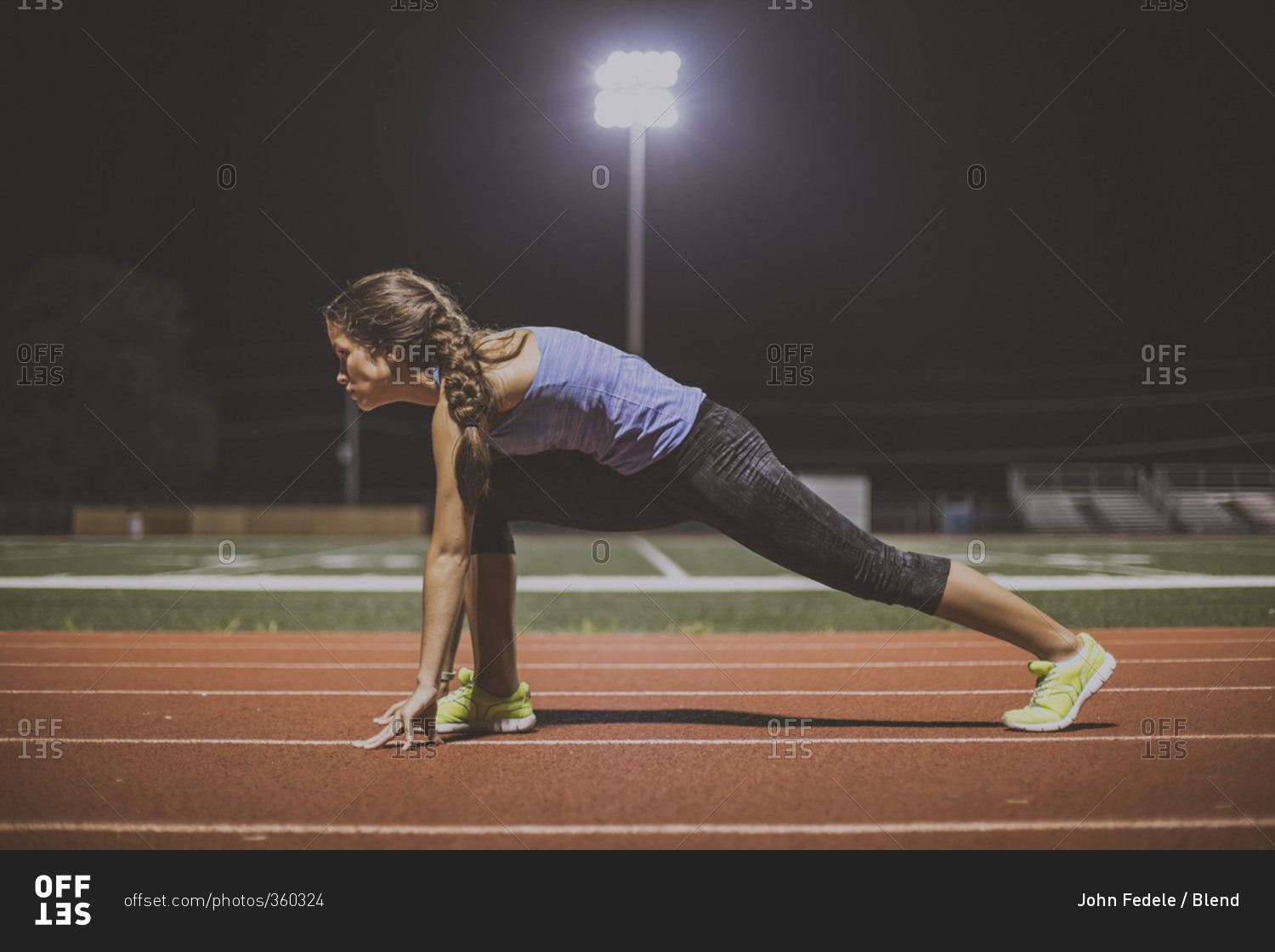 Mixed race runner in starting position on sports field