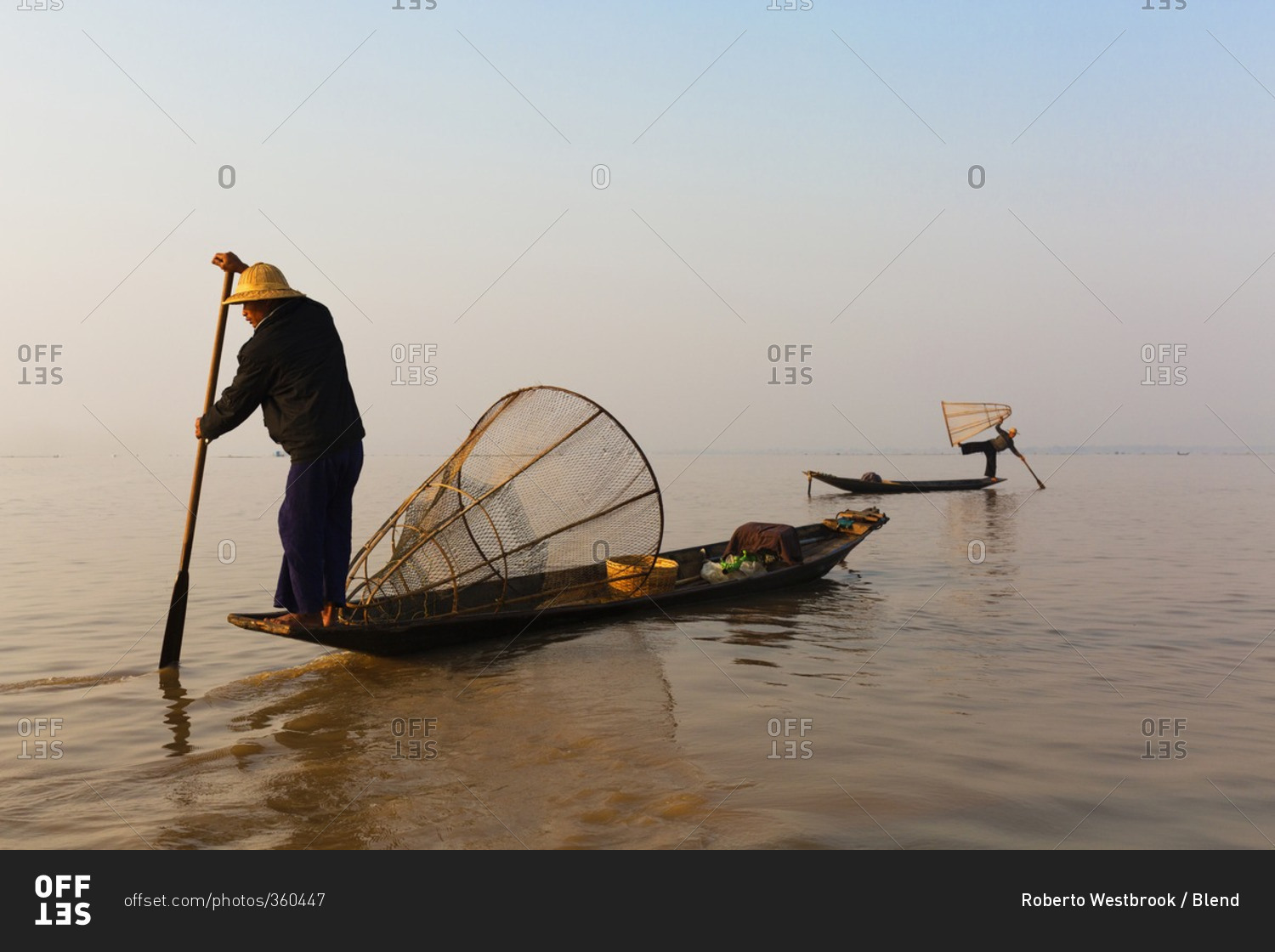 Asian fisherman rowing canoe on still lake