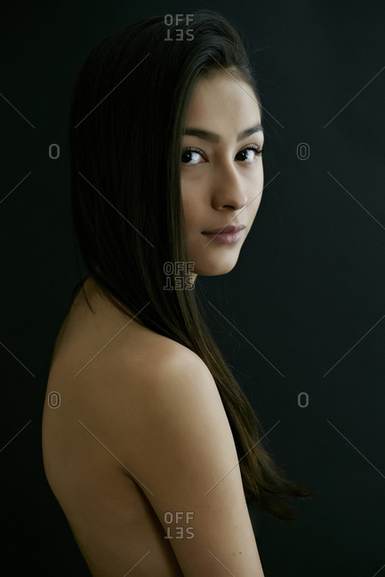 Nude Hispanic woman looking over shoulder stock photo