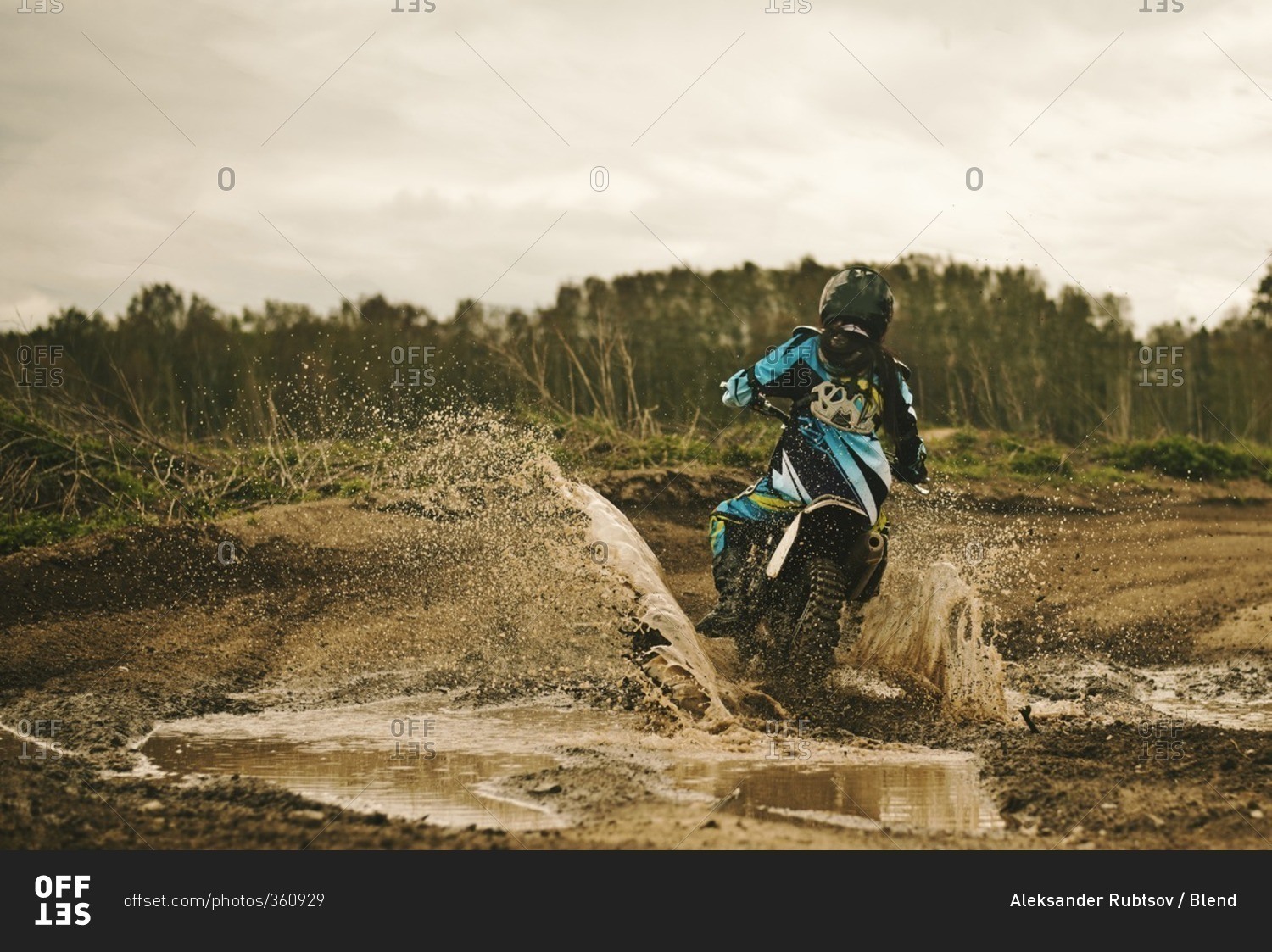 Caucasian man riding dirt bike in puddle