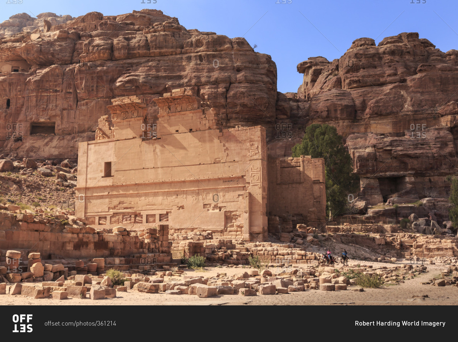 Local men on donkeys pass Qasr al-Bint temple, City of Petra ruins, Petra, Jordan, Middle East