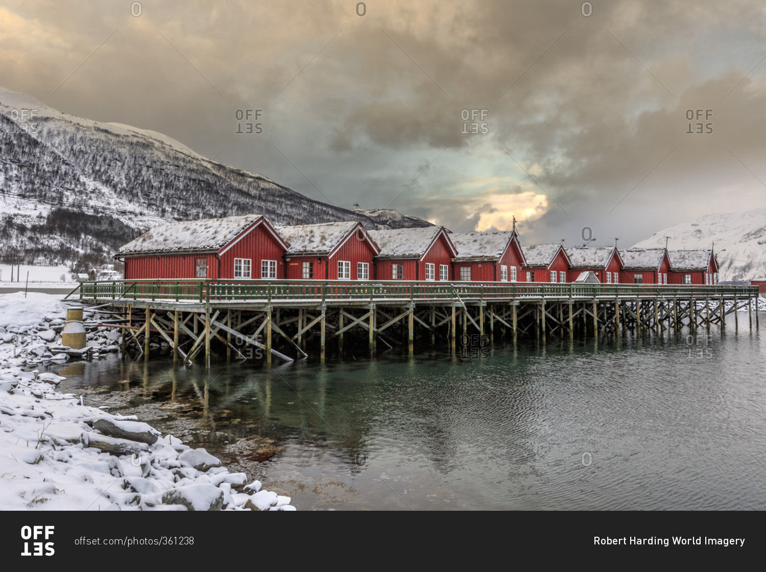 Typical red wooden huts of fishermen in the snowy and icy landscape of Lyngen Alps Tromso Lapland Norway Europe