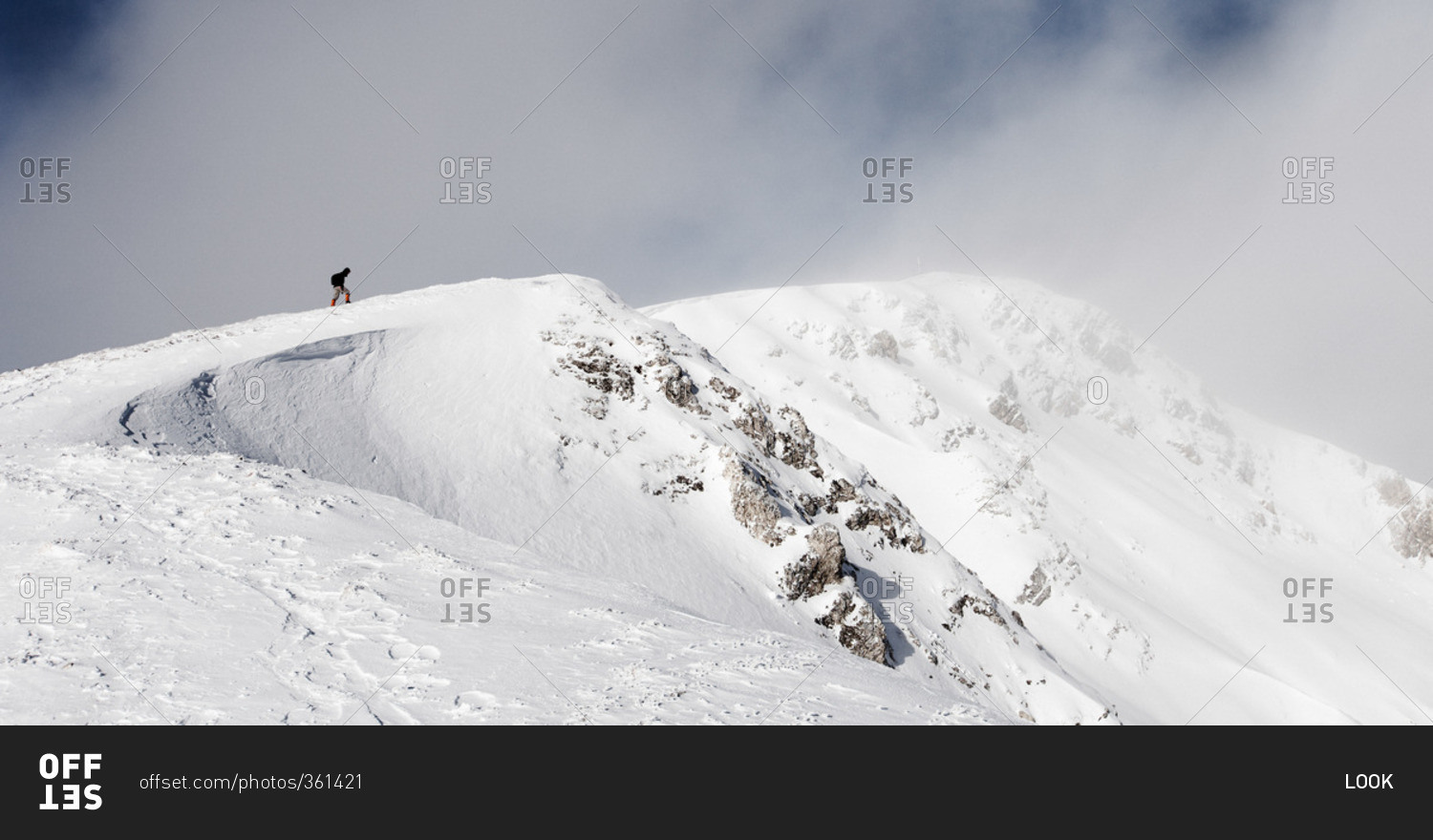 Hiker climbing on a snowy peak, ascend to Unnutz Mountain