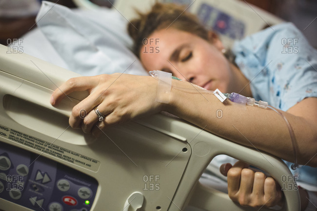 Woman gripping rail of hospital bed while in labor