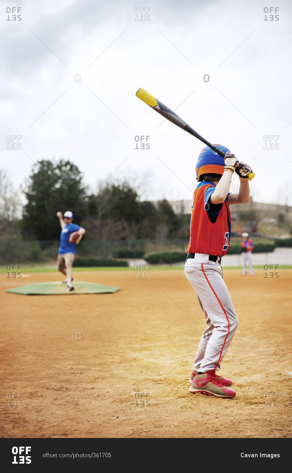 Side view of boy playing baseball with coach on field against sky