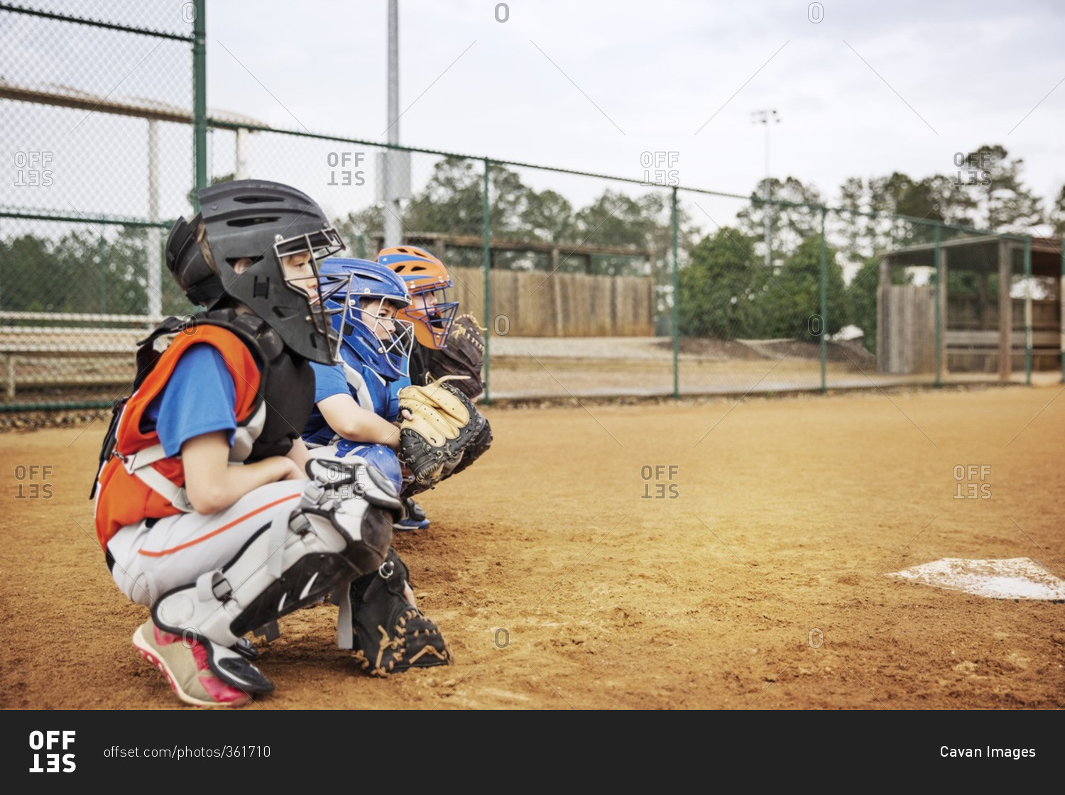 Side view of baseball catchers crouching on field
