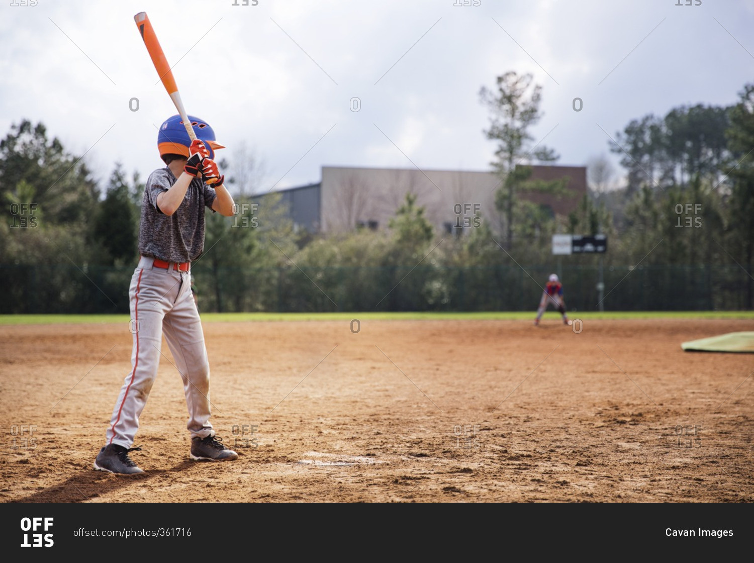 Side view of boy swinging baseball bat on field