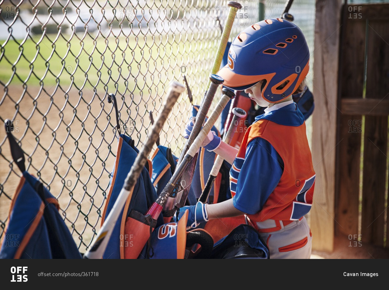 Side view of boy removing baseball bat from bag at field