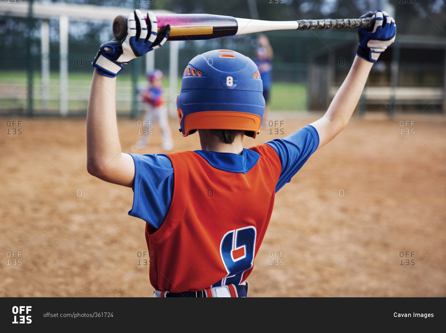 Rear view of boy holding baseball bat on field