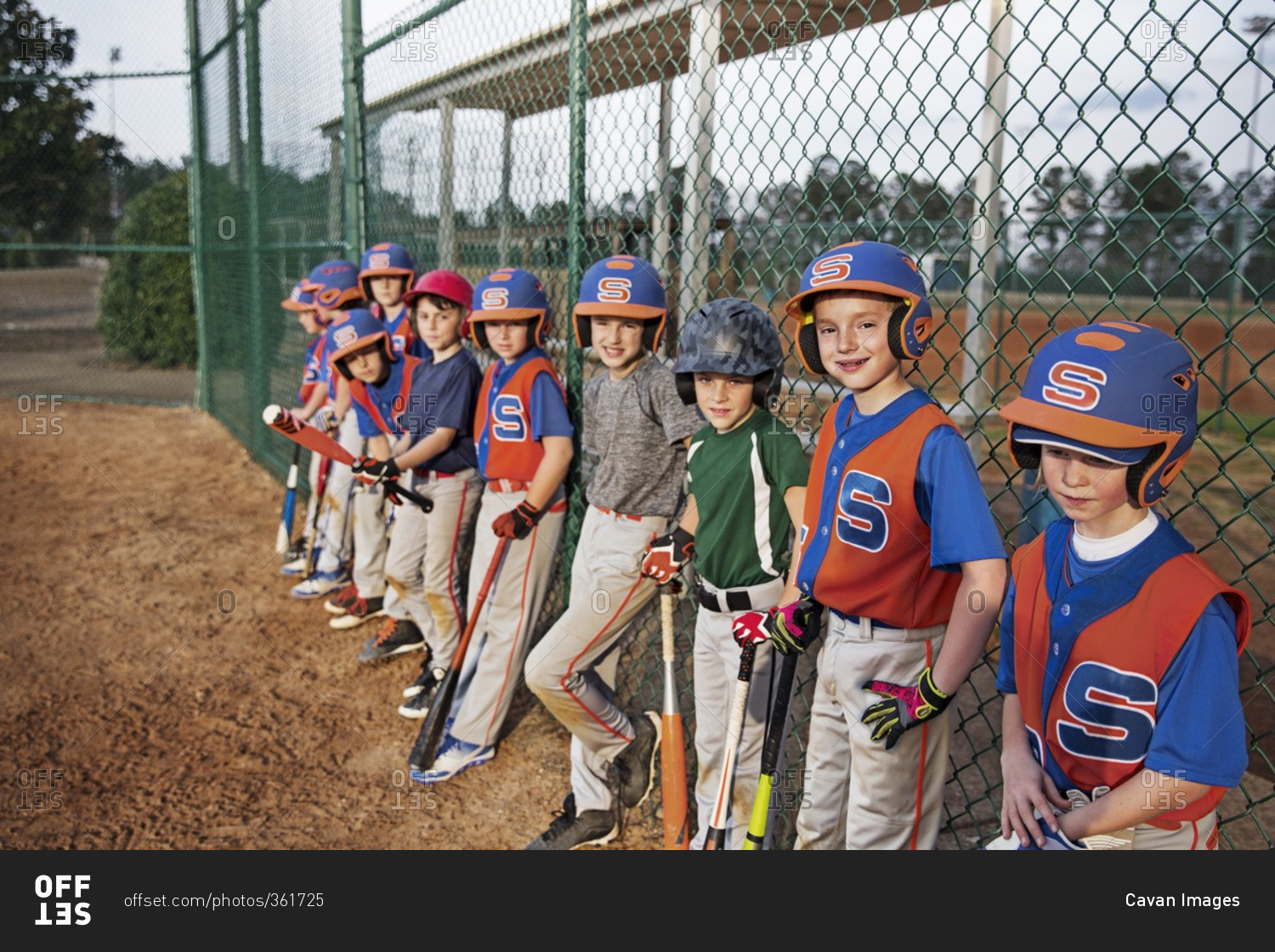 Baseball team standing by chain-link fence on field