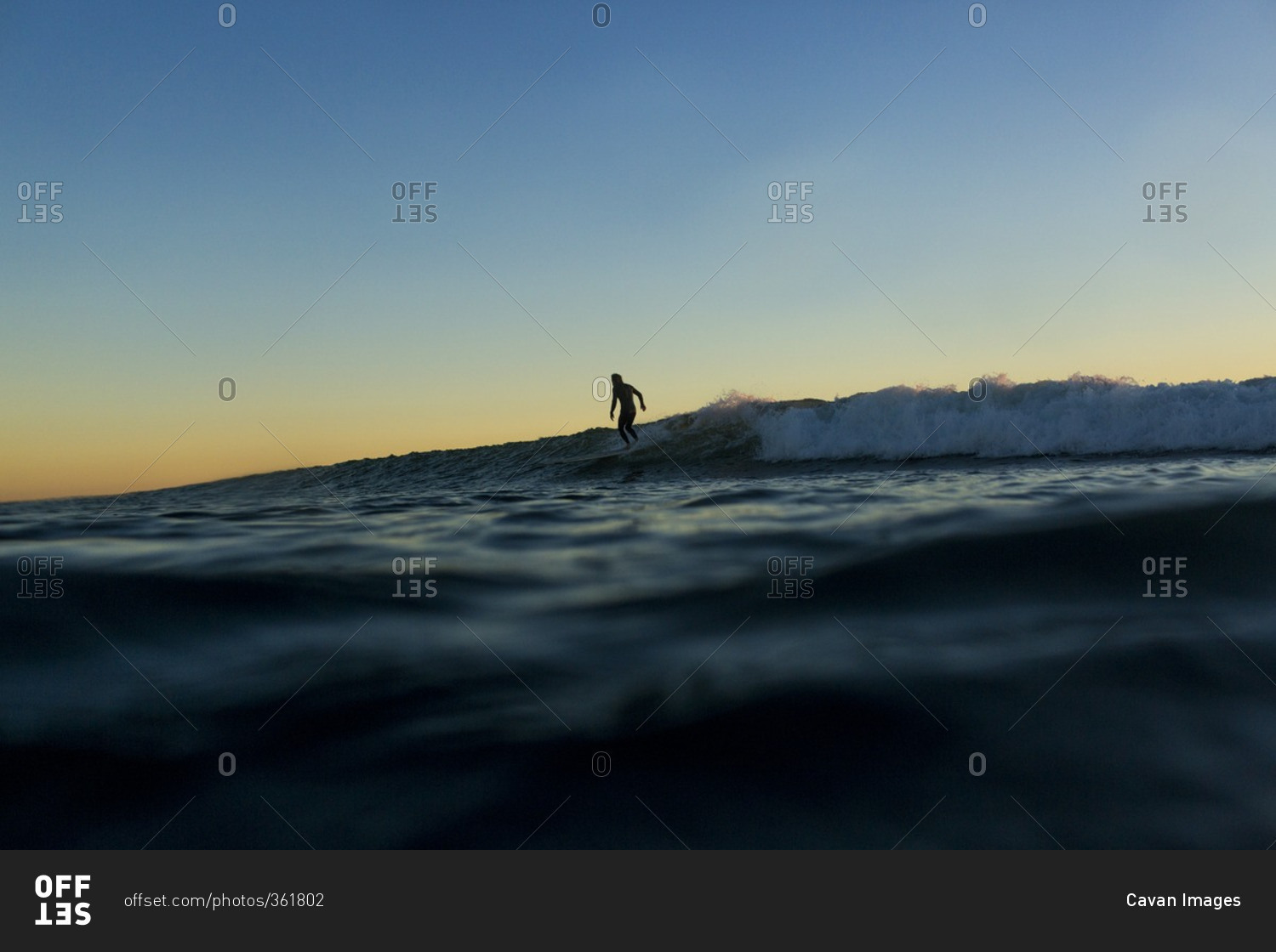 Distant view of silhouette man surfing on sea during sunset